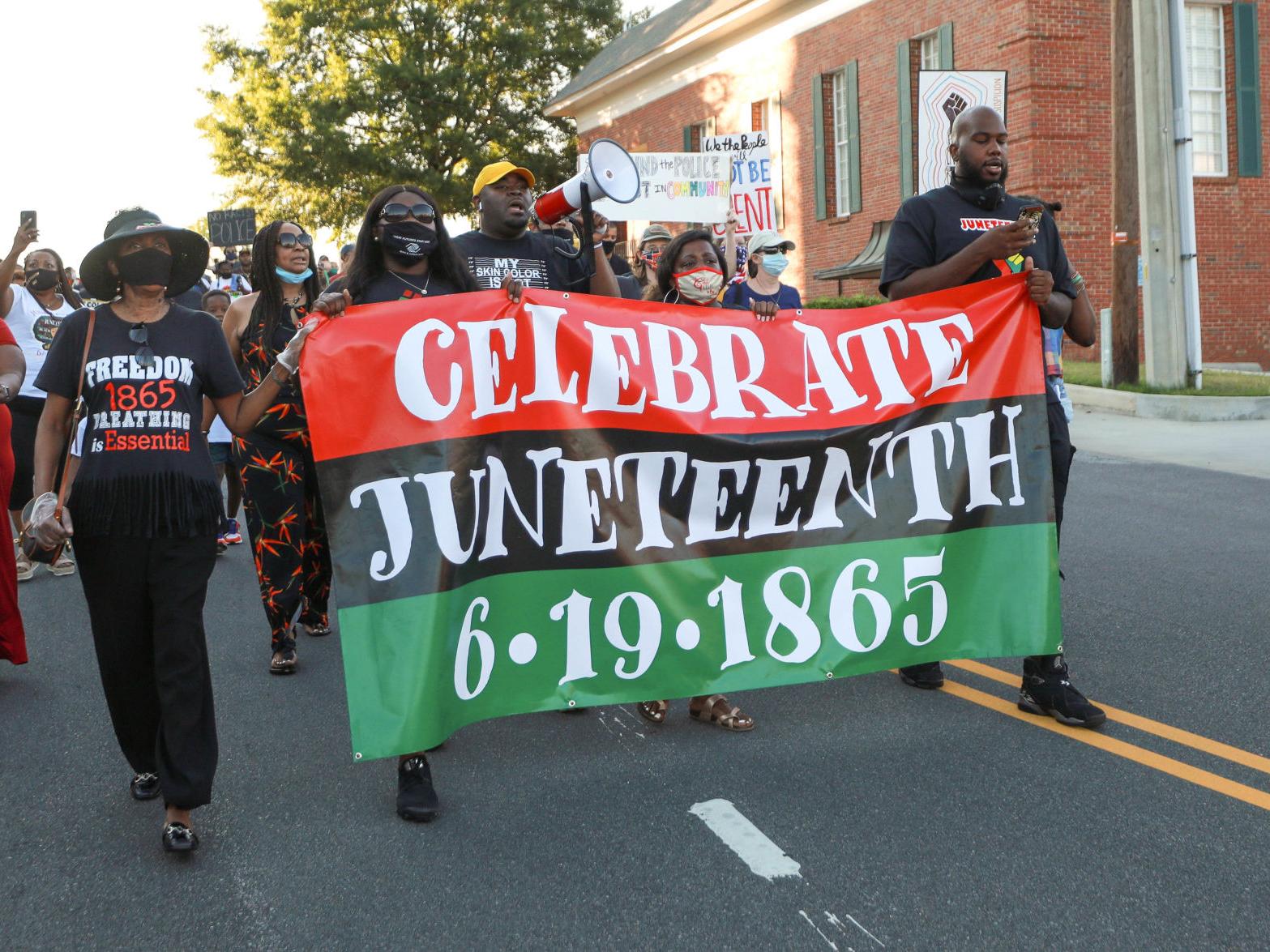 People marching while holding a Juneteenth banner
