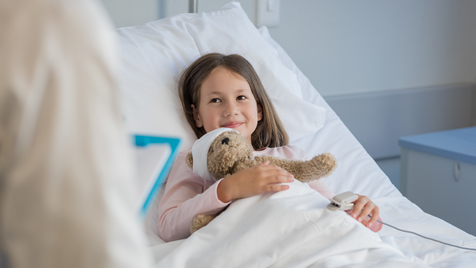 Child in hospital bed holding a teddy bear