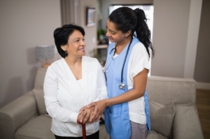 Young CNA helps an elderly woman with her cane